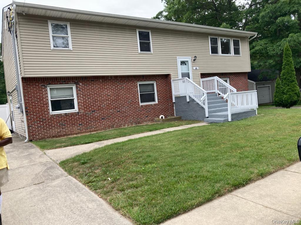 Split foyer home featuring brick siding and a front lawn
