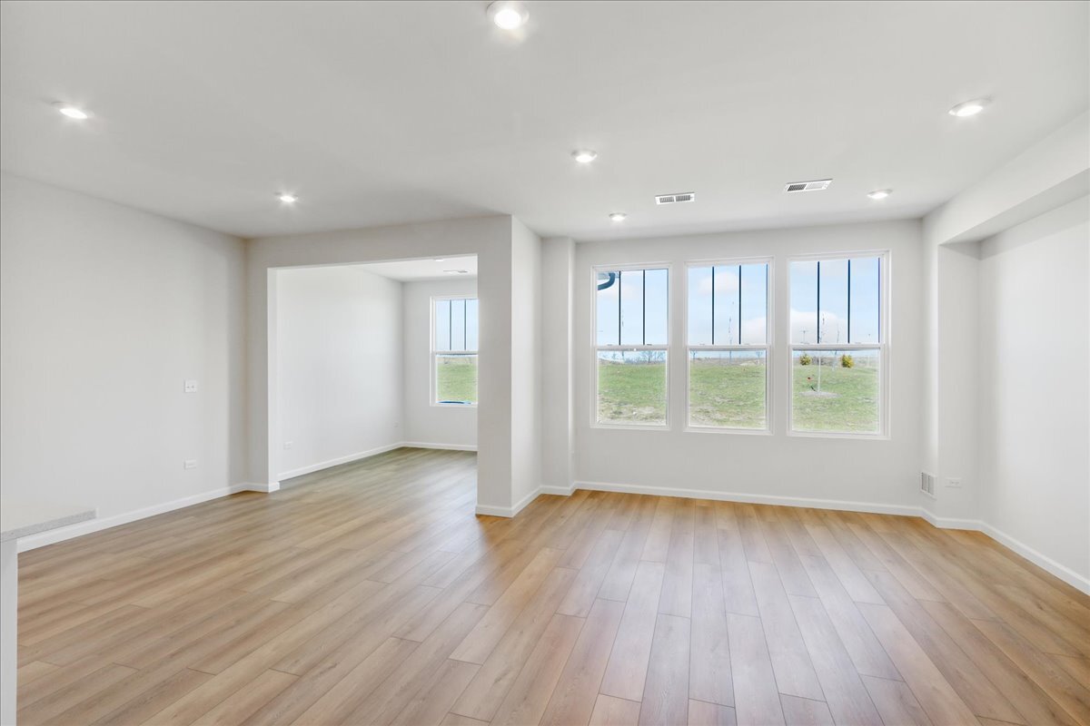 692 Switchgrass Way, Unit 57004 Bolingbrook, IL 60490 - Photo 12 of 25 a view of an empty room with wooden floor and a window
