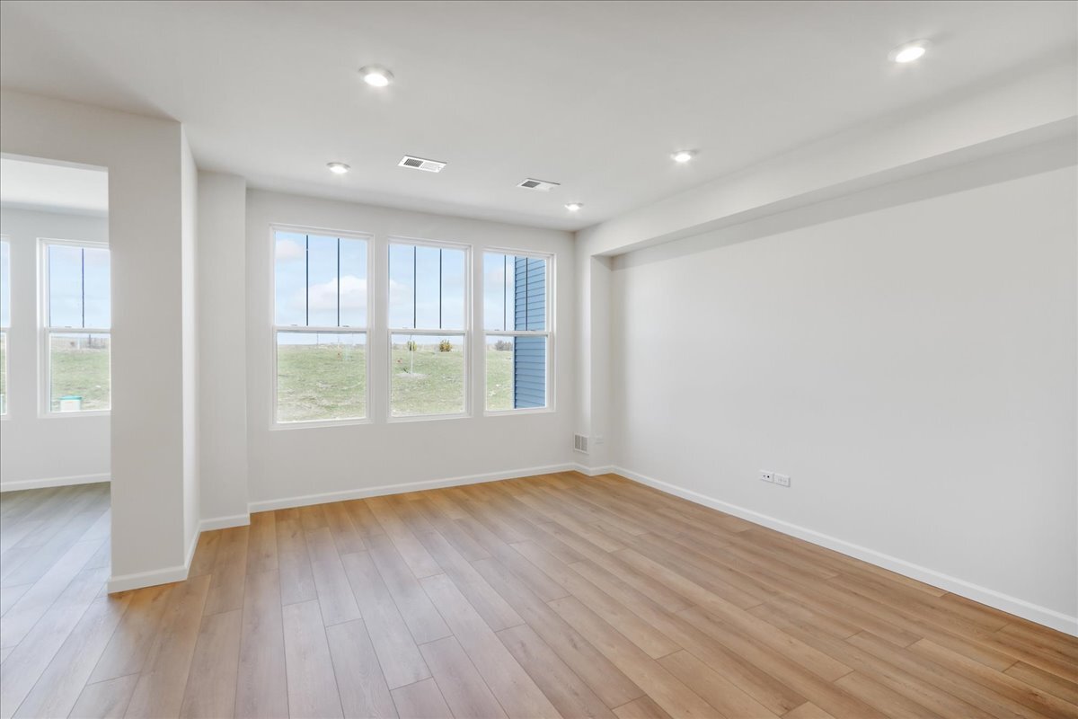 692 Switchgrass Way, Unit 57004 Bolingbrook, IL 60490 - Photo 16 of 25 an empty room with wooden floor and windows
