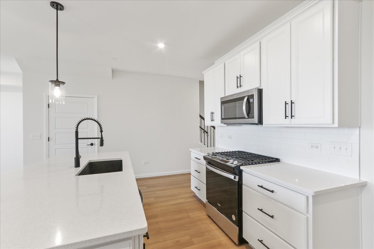 692 Switchgrass Way, Unit 57004 Bolingbrook, IL 60490 - Photo 9 of 25 a kitchen with stainless steel appliances granite countertop a stove a sink and a white refrigerator with white countertops