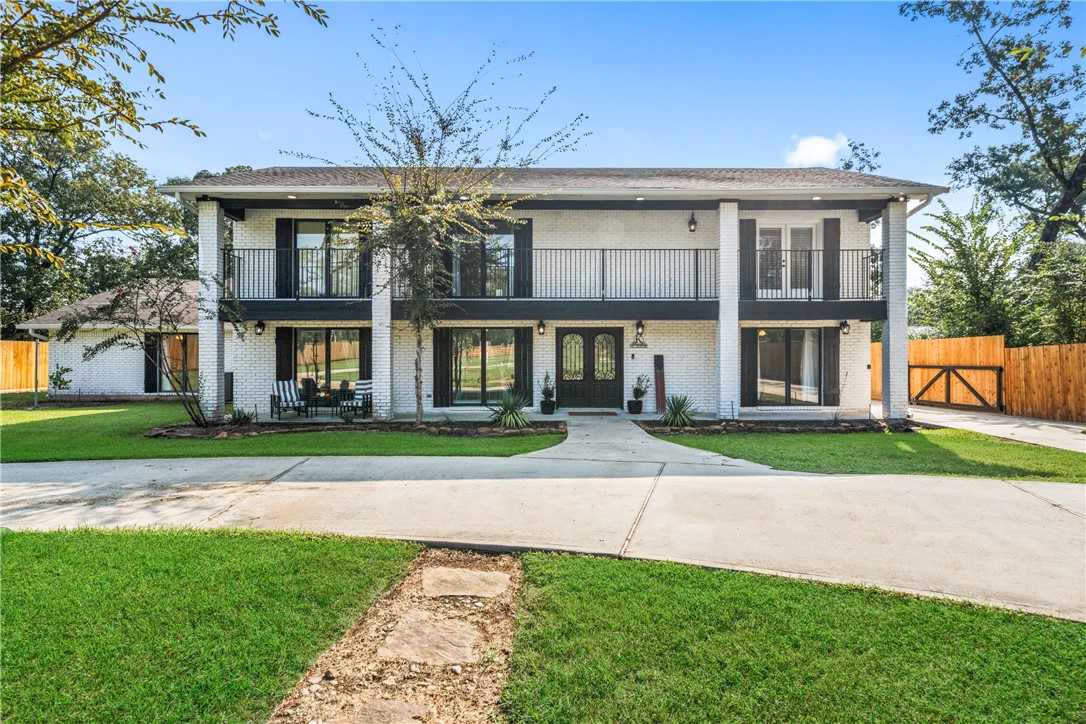 View of front of house featuring a balcony, brick siding, and french doors