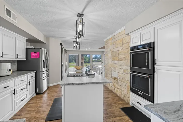 a kitchen with granite countertop a sink a counter space appliances and cabinets
