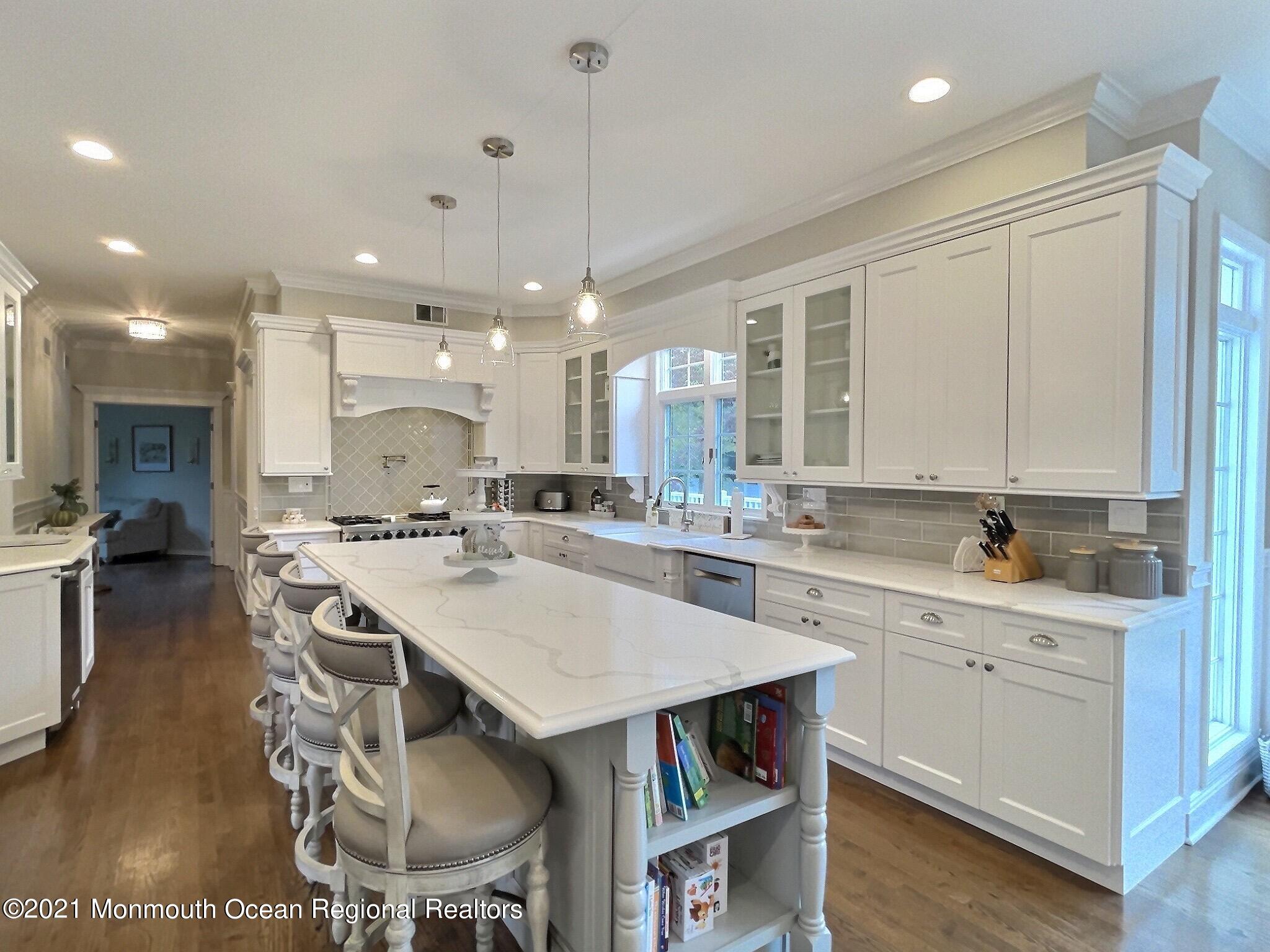 21 Dearborn Drive Holmdel, NJ 07733 - Photo 4 of 48 a kitchen with kitchen island a dining table chairs sink and white cabinets