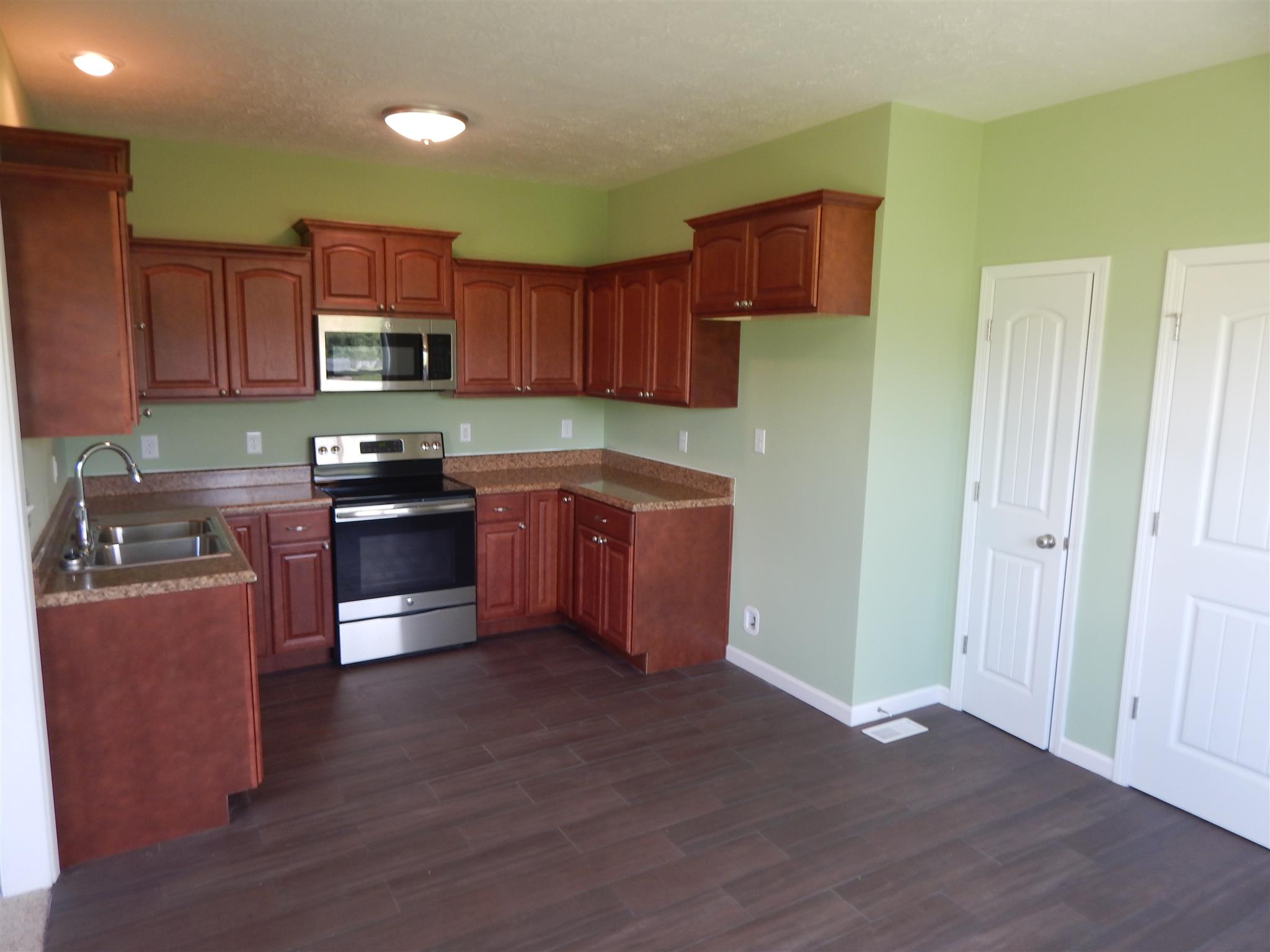 574 Cook Road Portland, TN 37148 - Photo 6 of 12 a kitchen with stainless steel appliances granite countertop a stove top oven a sink dishwasher and a refrigerator with wooden floor