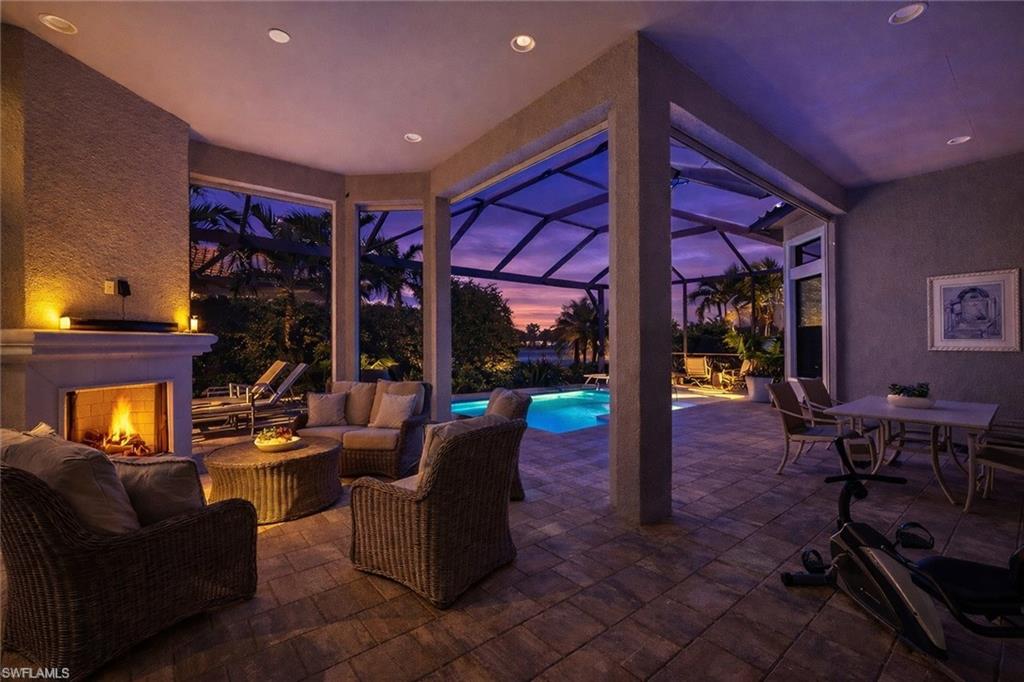 8667 Amour Court Naples, FL 34119 - Photo 35 of 47 Patio terrace at dusk with a patio area, glass enclosure, a sunroom, an outdoor living / dining area, and an outdoor pool