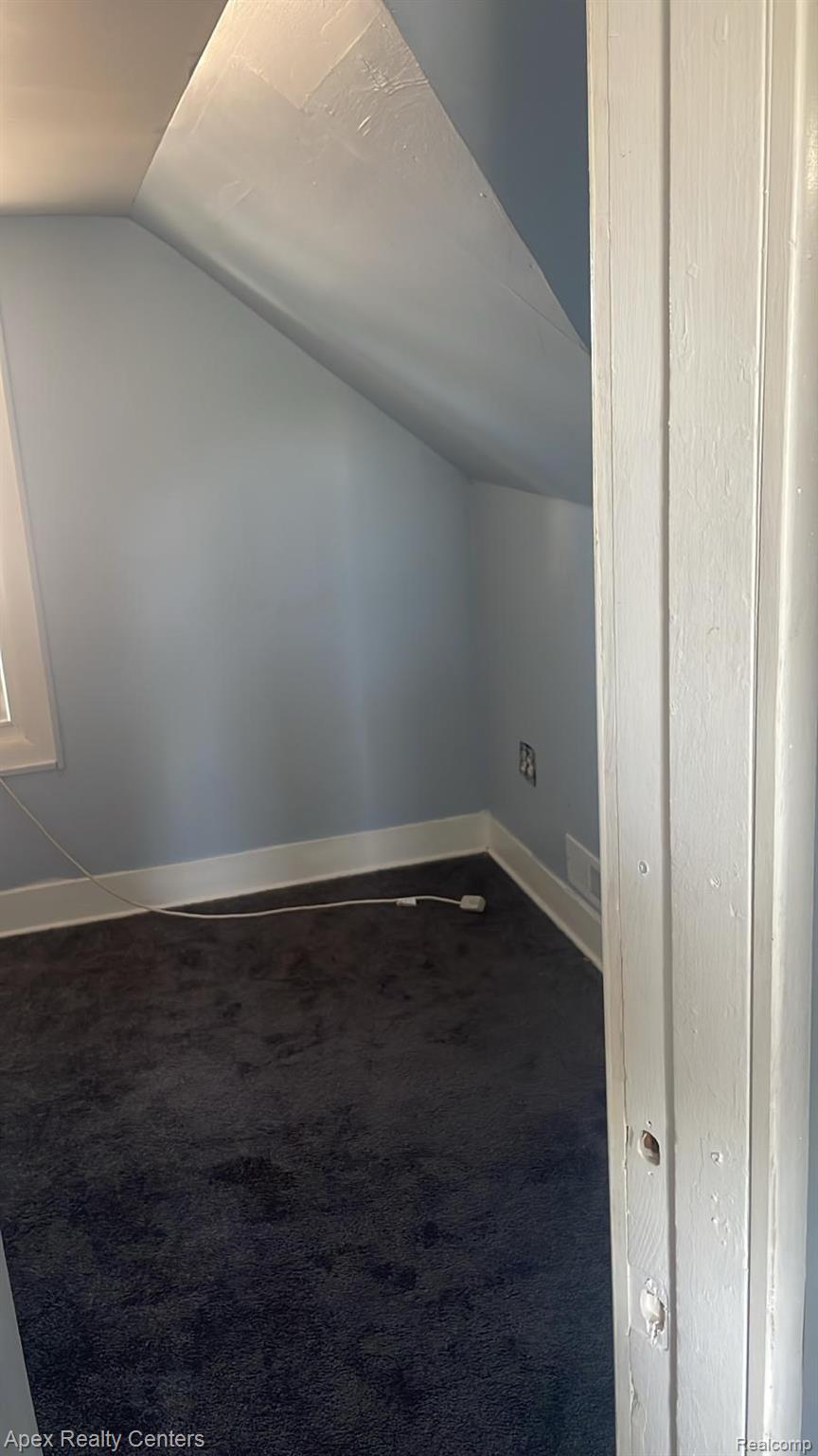 6730 Forrer Street Detroit, MI 48228 - Photo 6 of 10 Interior room featuring angled walls, light blue paint, dark carpet, and white baseboards