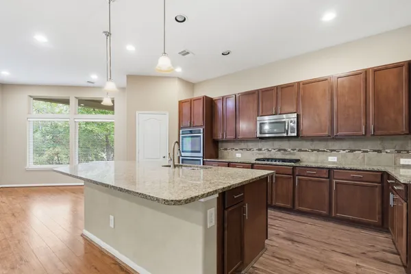 a kitchen with stainless steel appliances granite countertop a sink a stove and a wooden floors
