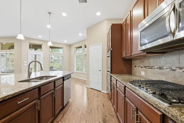 a kitchen with stainless steel appliances granite countertop a stove a sink dishwasher and a microwave oven with wooden floor