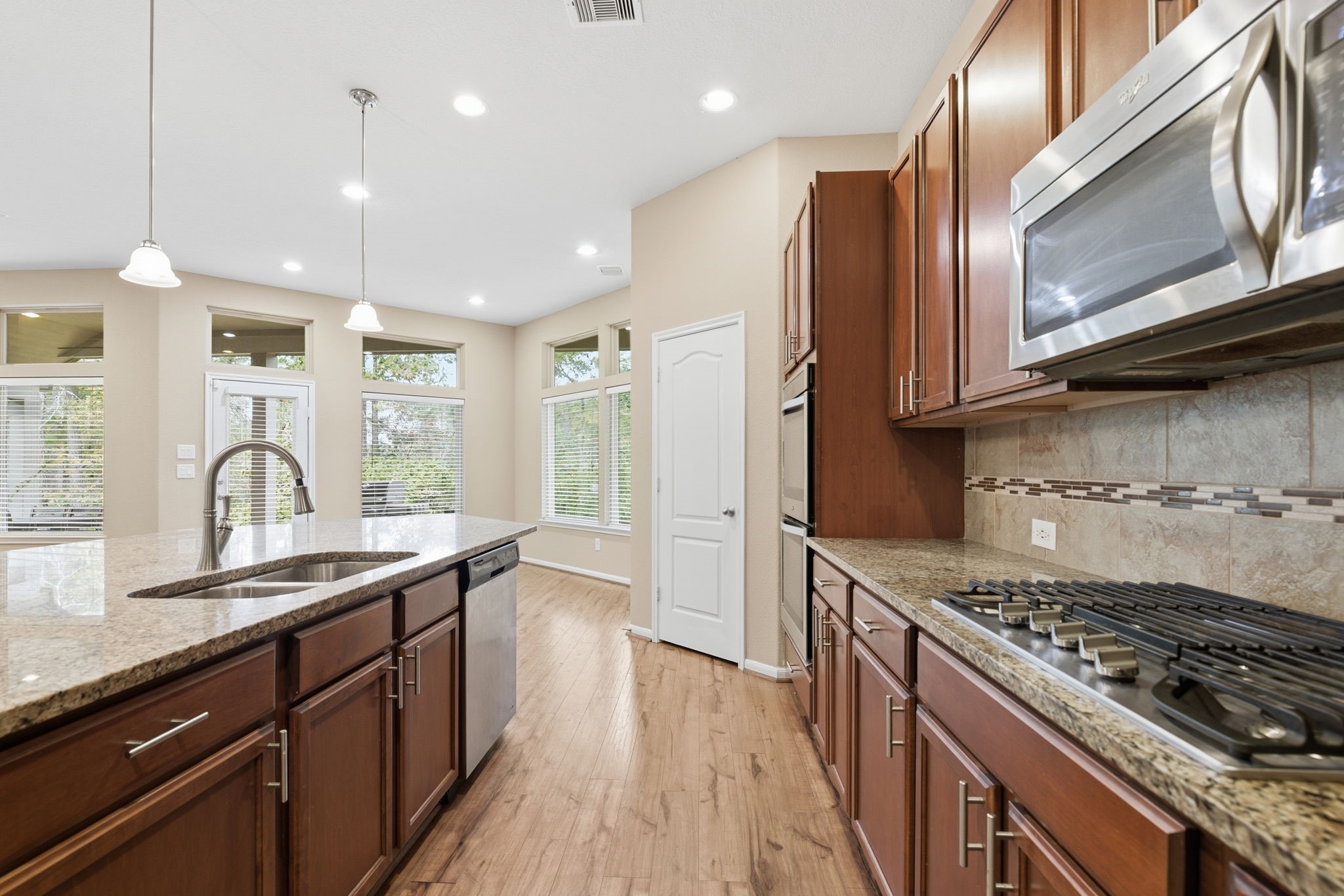 1810 Nantz Lane Conroe, TX 77304 - Photo 7 of 23 a kitchen with stainless steel appliances granite countertop a stove a sink dishwasher and a microwave oven with wooden floor