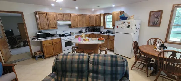 a kitchen with stainless steel appliances granite countertop a dining table chairs and a refrigerator