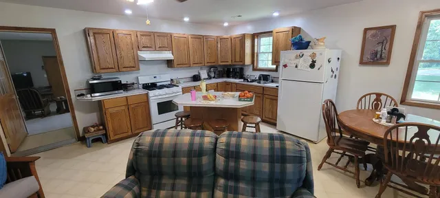 a kitchen with stainless steel appliances granite countertop a dining table chairs and a refrigerator