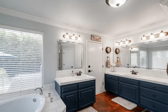 a bathroom with a tub sink double vanity granite and a mirror