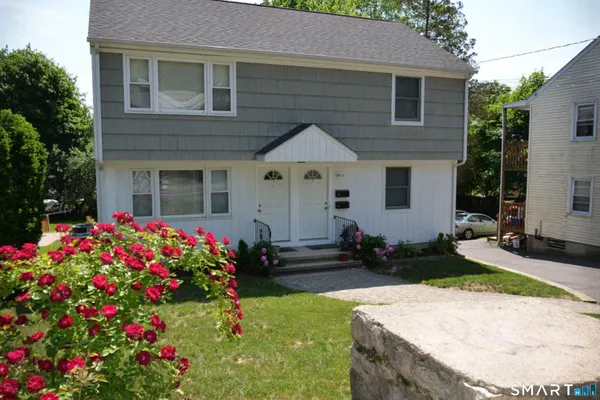 a front view of house and yard with beautiful flowers and green space