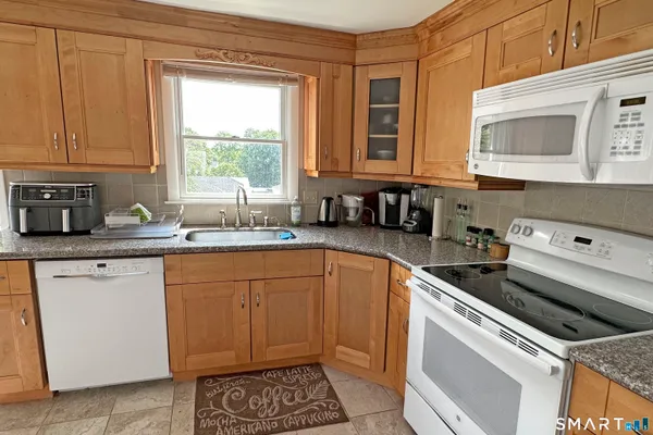 a kitchen with granite countertop a sink stainless steel appliances a window and a counter top space