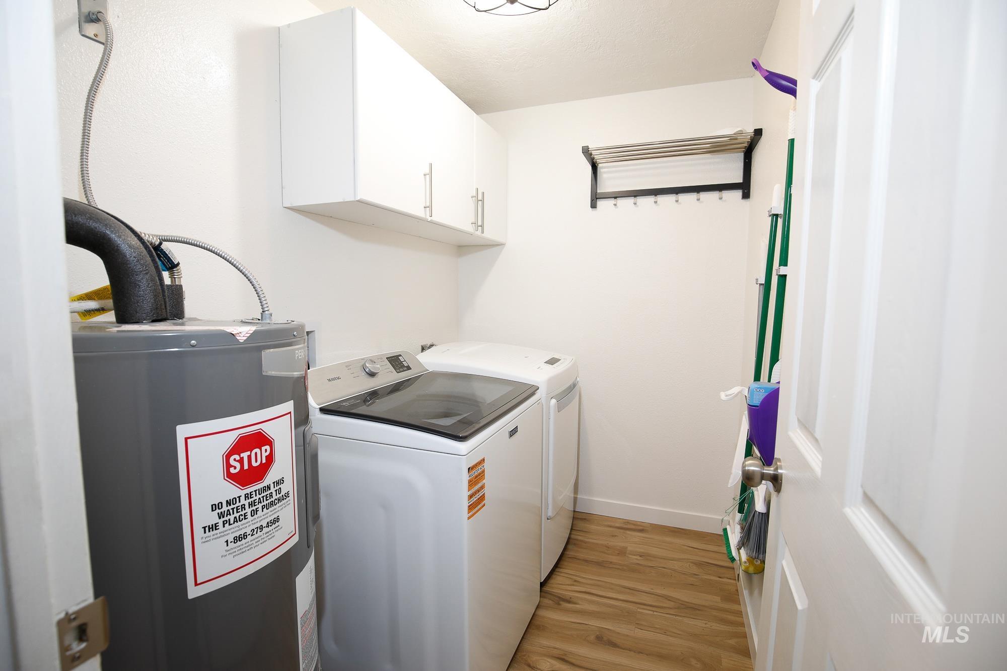 10534 West Fox Ridge Drive Boise, ID 83709 - Photo 2 of 15 Laundry area featuring electric water heater, light wood-style floors, separate washer and dryer, and cabinet space