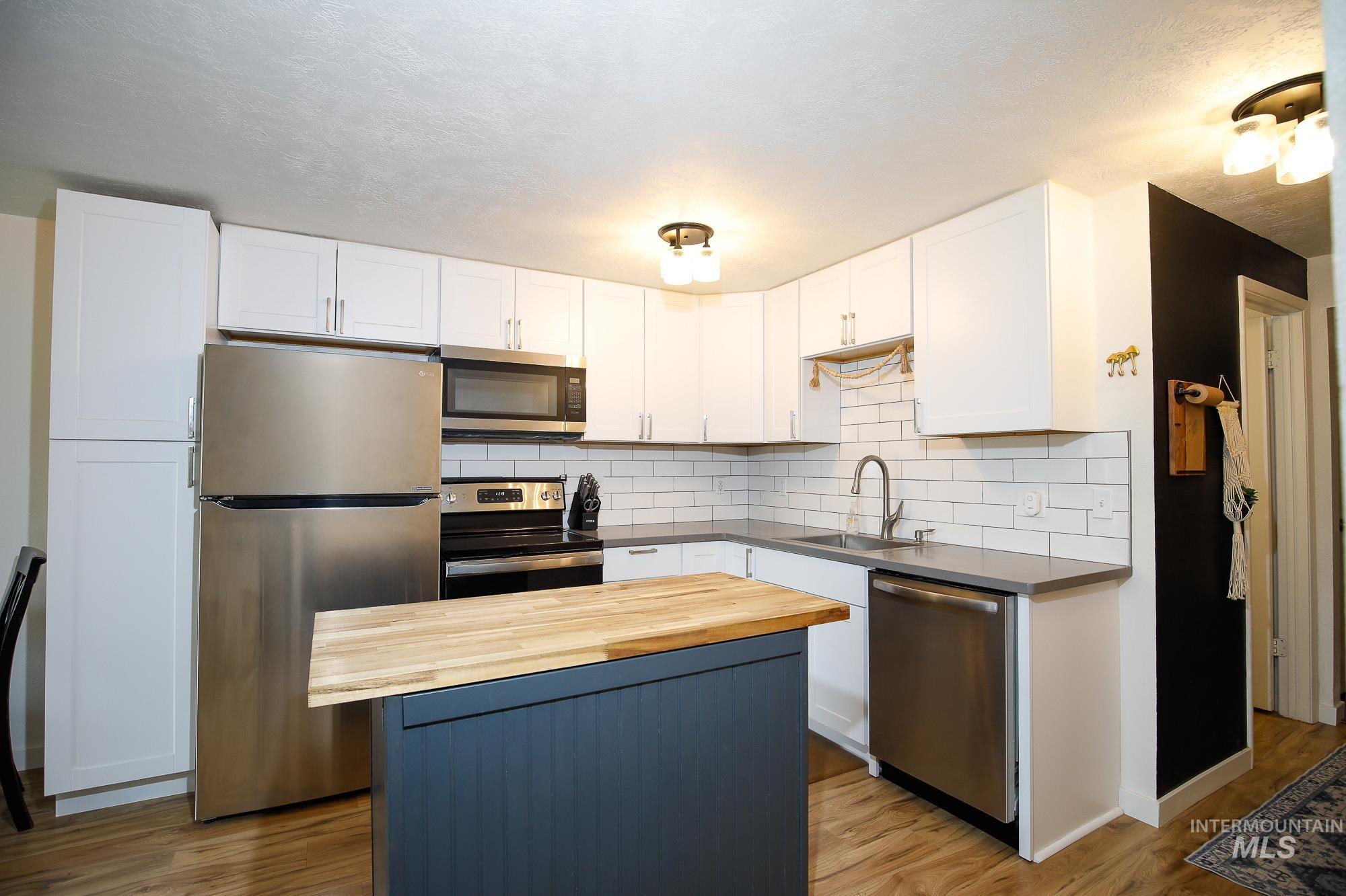 10534 West Fox Ridge Drive Boise, ID 83709 - Photo 3 of 15 Kitchen featuring wood counters, stainless steel appliances, a kitchen island, and white cabinetry