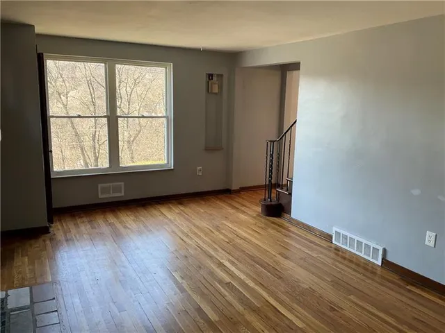 an empty room with wooden floor and a window