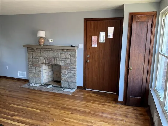 a view of an empty room with wooden floor and a fireplace