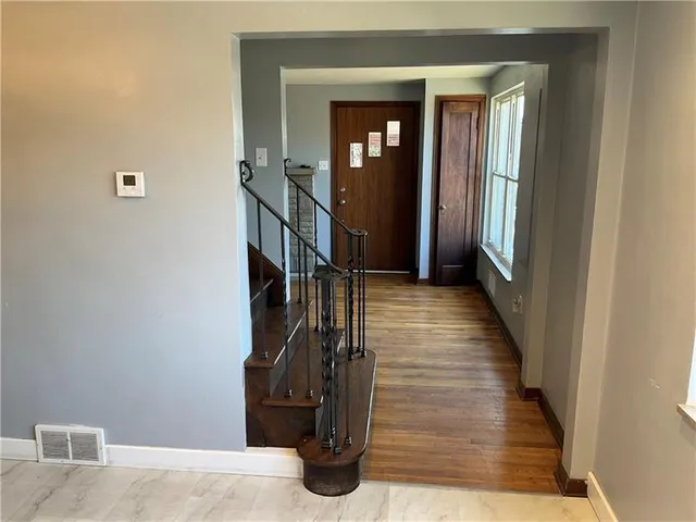 a view of a hallway with wooden floor and stairs