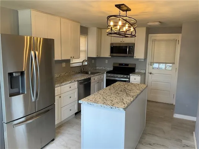 a kitchen with granite countertop stainless steel appliances a stove refrigerator and microwave