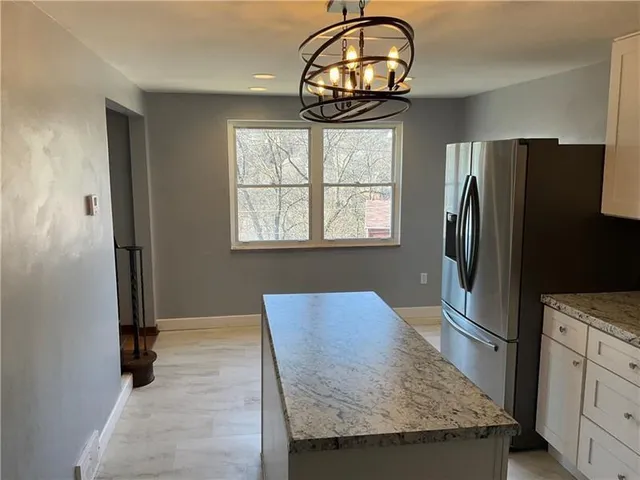 a view of kitchen with granite countertop kitchen island a refrigerator wooden floor and a sink