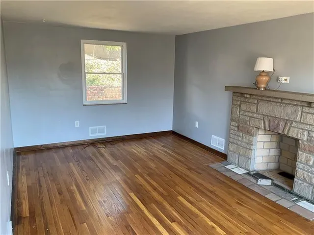 a view of wooden floor fire place and windows in a room