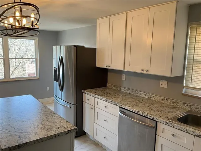 a kitchen with granite countertop a refrigerator sink and cabinets