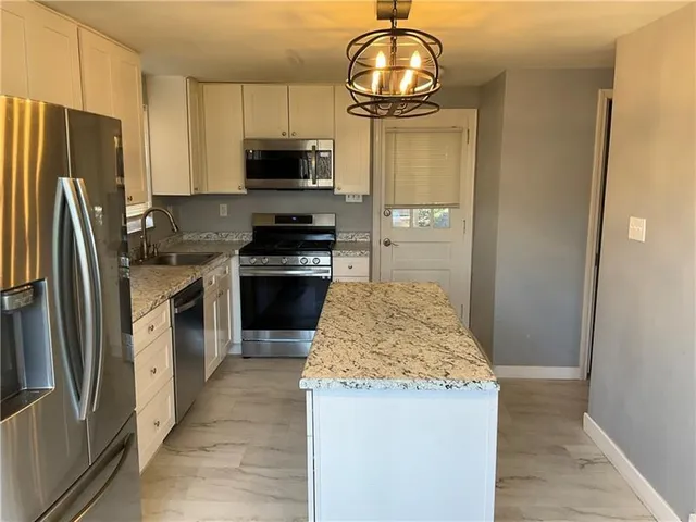 a kitchen with stainless steel appliances granite countertop a stove refrigerator and microwave