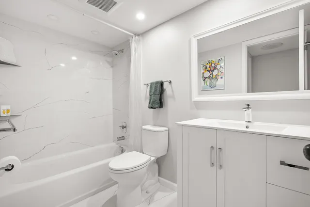 a bathroom with a bathtub shower sink mirror and toilet