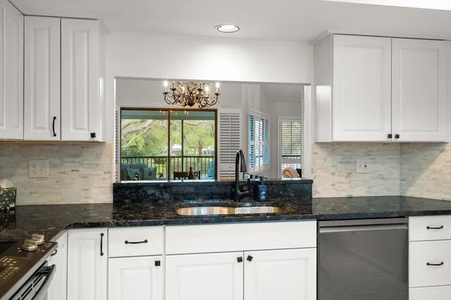 a kitchen with granite countertop a sink and a white cabinets