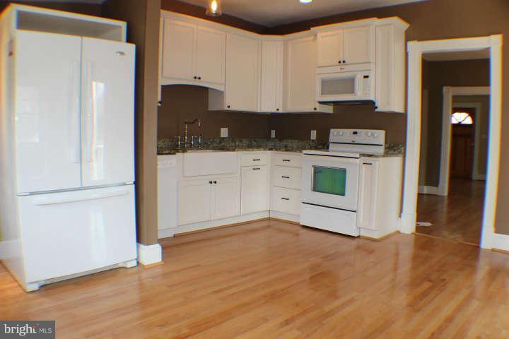 10304 Gunston Road Lorton, VA 22079 - Photo 12 of 30 a kitchen with stainless steel appliances a stove a refrigerator a sink and white cabinets with wooden floor