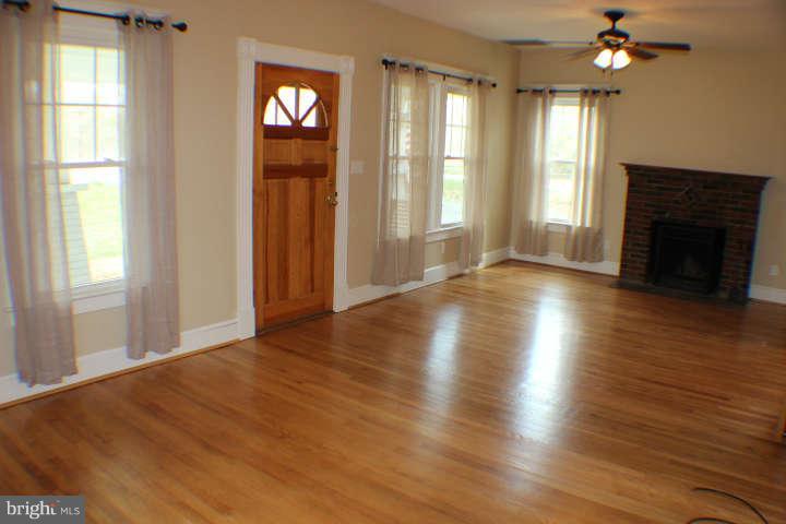 10304 Gunston Road Lorton, VA 22079 - Photo 4 of 30 an empty room with wooden floor fireplace and windows