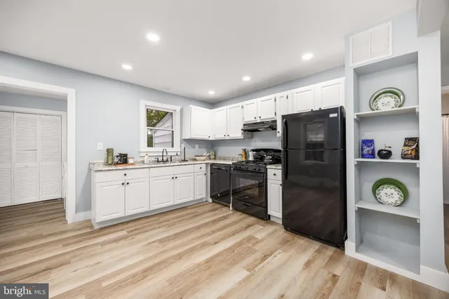 a kitchen with granite countertop a refrigerator and a stove top oven