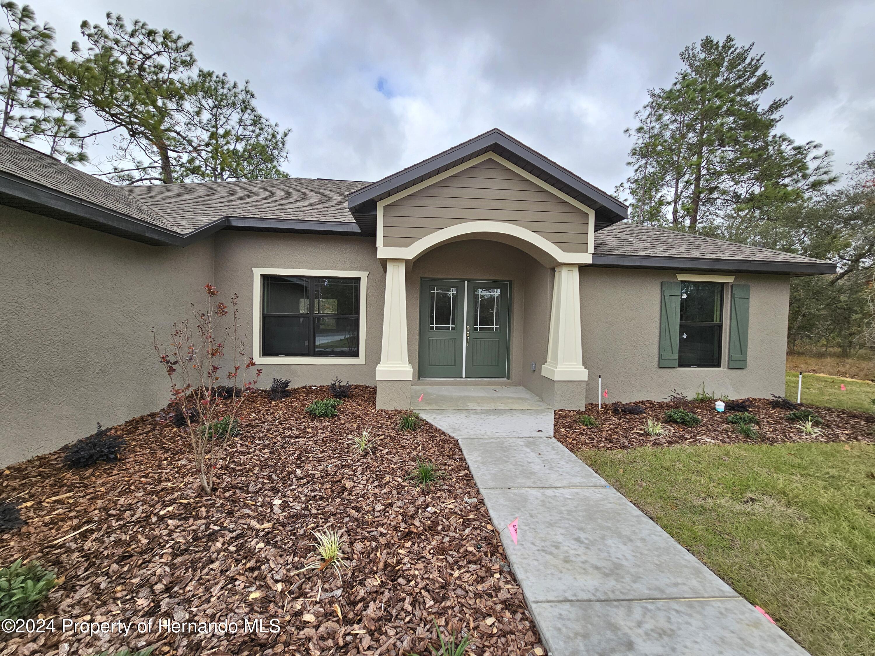 13365 Ruffed Grouse Road Weeki Wachee, FL 34614 - Photo 3 of 18 a front view of a house with a garden