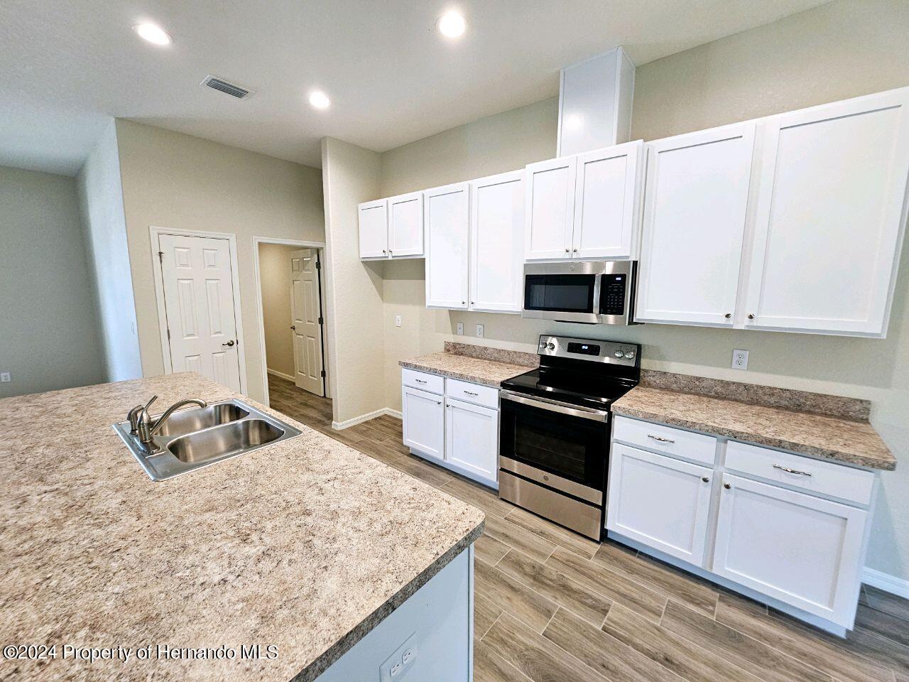 13365 Ruffed Grouse Road Weeki Wachee, FL 34614 - Photo 7 of 18 a kitchen with granite countertop a sink stove and cabinets