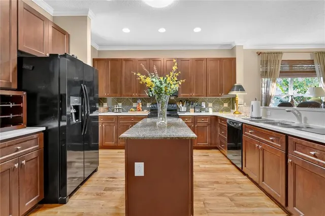 a kitchen with stainless steel appliances granite countertop a refrigerator a sink dishwasher a oven and a dining table with wooden floor