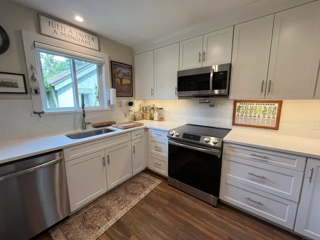 a kitchen with stainless steel appliances granite countertop a sink a stove and a microwave