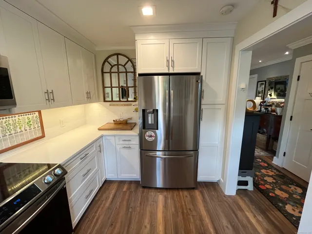 a kitchen with granite countertop a refrigerator stove and wooden floor