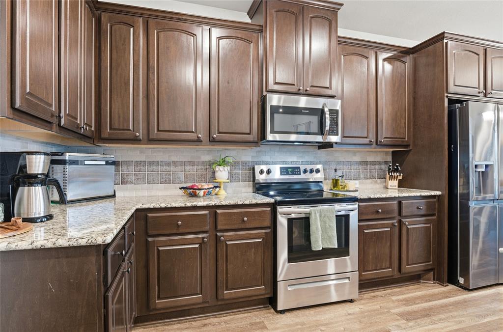 1292 Whiskey Hollow Road West, TX 76691 - Photo 11 of 34 Kitchen with stainless steel appliances, light stone countertops, dark brown cabinets, and light wood-type flooring