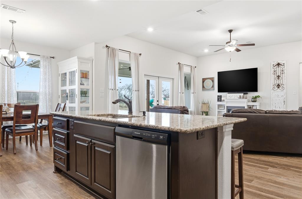 1292 Whiskey Hollow Road West, TX 76691 - Photo 34 of 34 Kitchen featuring dark brown cabinets, an island with sink, dishwasher, a ceiling fan, and open floor plan