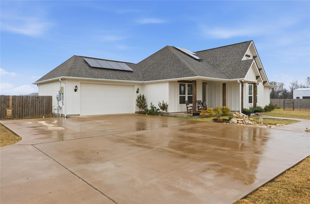 1292 Whiskey Hollow Road West, TX 76691 - Photo 26 of 34 View of home's exterior with roof with shingles, solar panels, driveway, covered porch, and a garage
