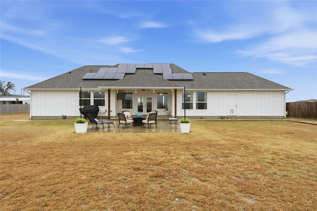 1292 Whiskey Hollow Road West, TX 76691 - Photo 27 of 34 Rear view of house with french doors, solar panels, a patio, and roof with shingles