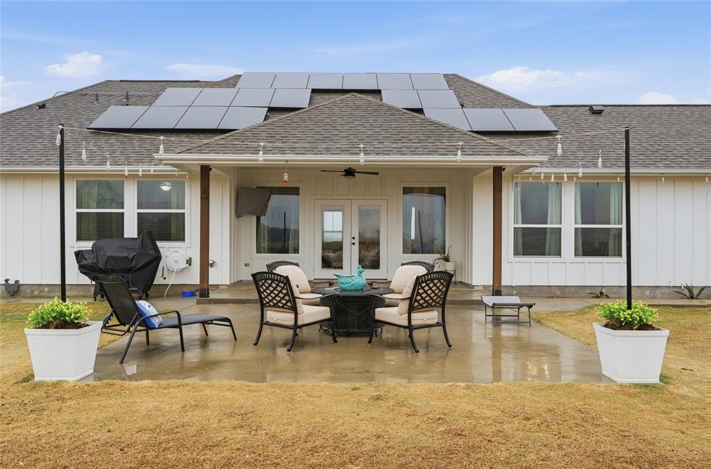 1292 Whiskey Hollow Road West, TX 76691 - Photo 28 of 34 Back of property with a shingled roof, board and batten siding, french doors, a ceiling fan, and solar panels