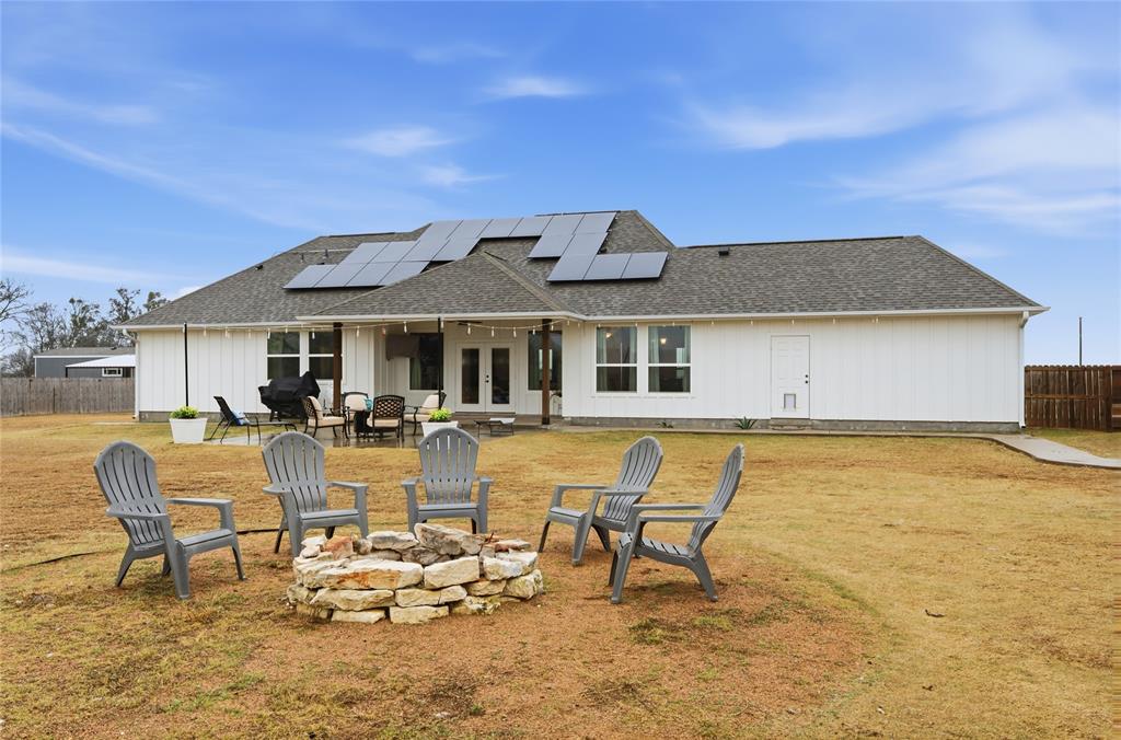 1292 Whiskey Hollow Road West, TX 76691 - Photo 30 of 34 Back of house with french doors, a patio area, solar panels, an outdoor fire pit, and a shingled roof
