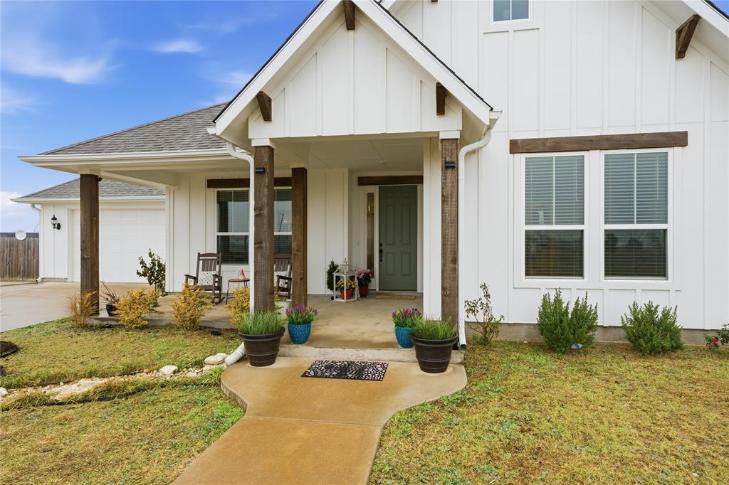 1292 Whiskey Hollow Road West, TX 76691 - Photo 5 of 34 View of front of home with board and batten siding, covered porch, a front lawn, and roof with shingles