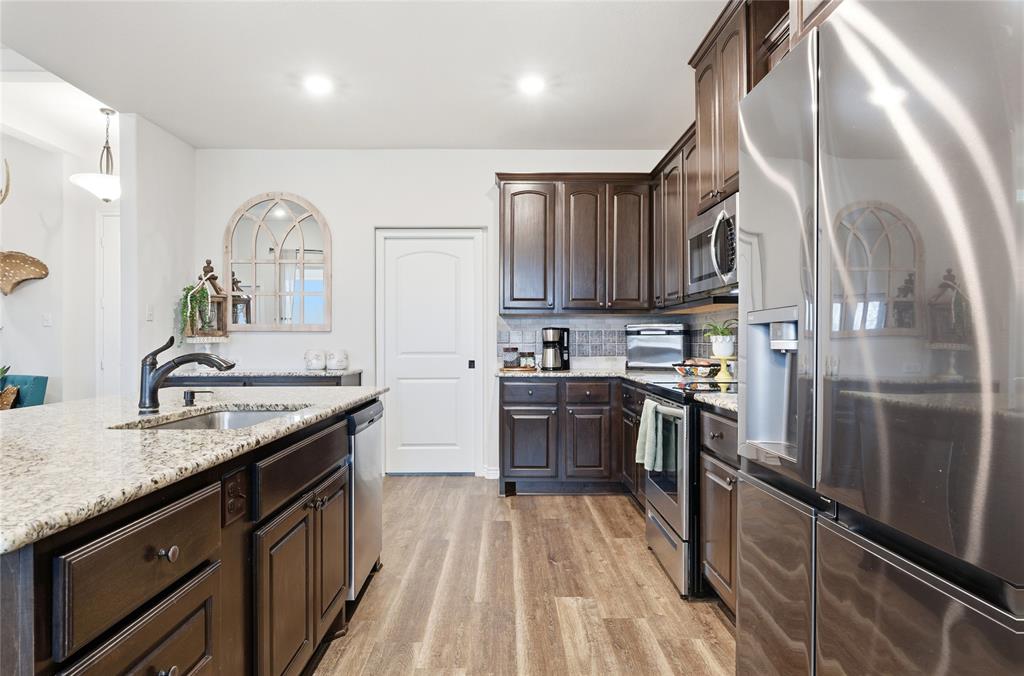 1292 Whiskey Hollow Road West, TX 76691 - Photo 10 of 34 Kitchen with appliances with stainless steel finishes, dark brown cabinetry, light stone countertops, light wood-style flooring, and recessed lighting