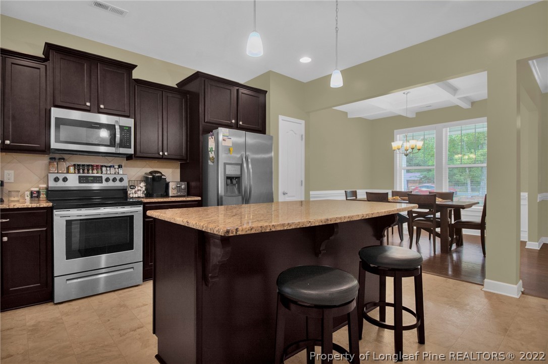 809 Montrose Road Raeford, NC 28376 - Photo 10 of 33 a kitchen with granite countertop a table chairs microwave and refrigerator