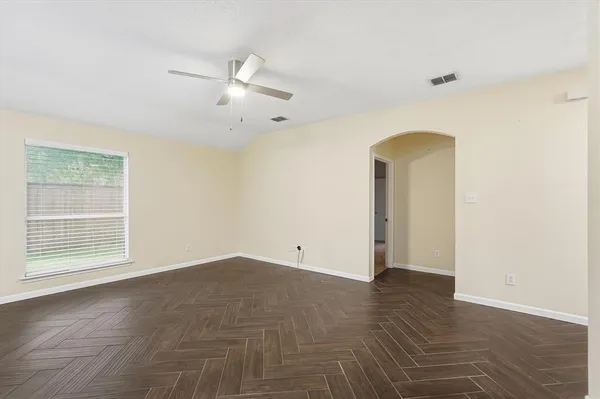 an empty room with wooden floor and windows