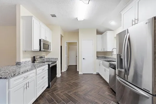 a kitchen with granite countertop a refrigerator stove and sink