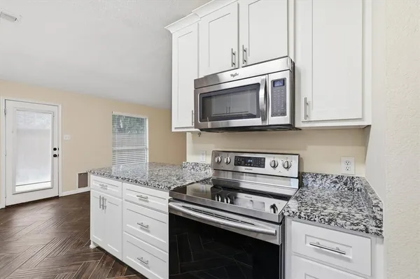 a kitchen with granite countertop cabinets stainless steel appliances and wooden floor